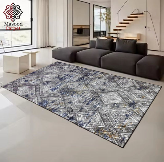 Patterned rug on a white floor with a modern sofa and decor in the background, featuring the Masood Carpet logo.